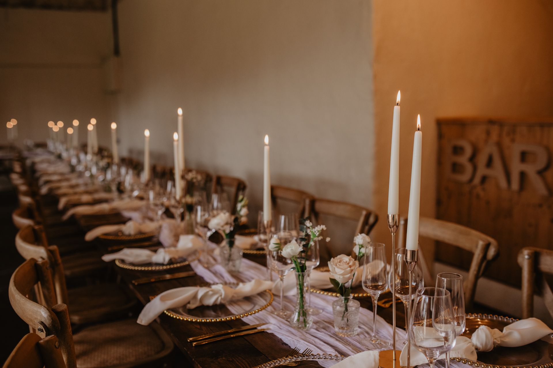 A long table with candles and plates set for a wedding reception.