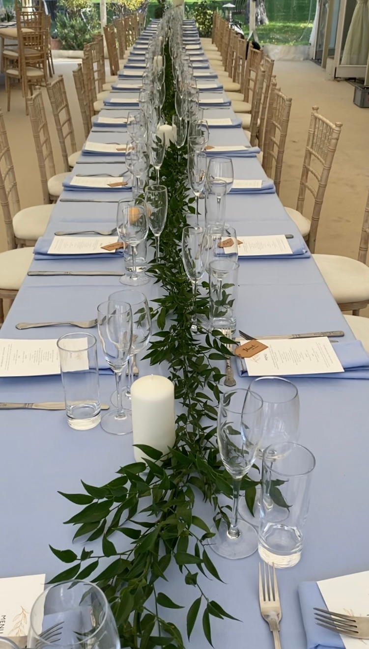 A long table with plates , glasses , candles and flowers on it.