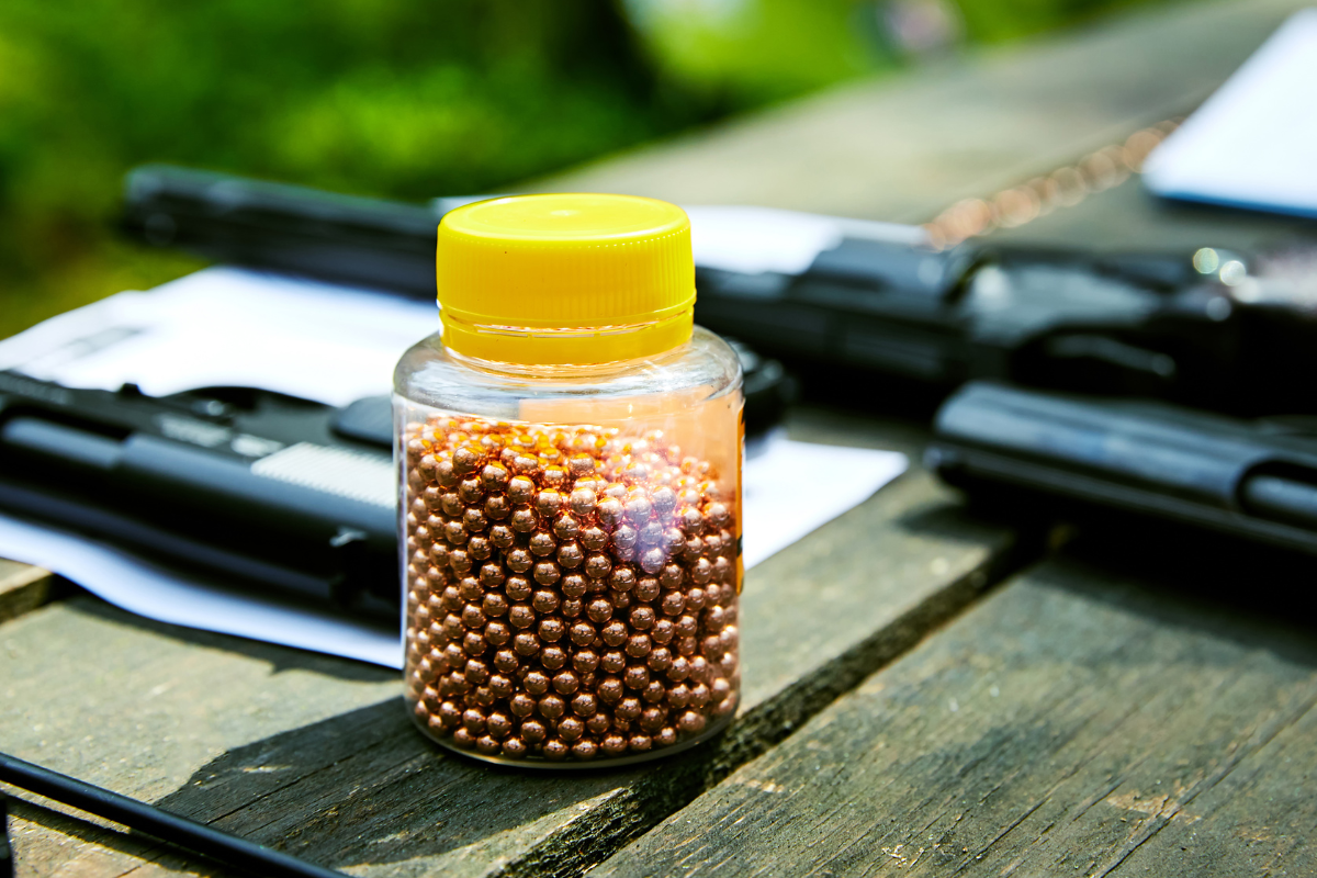 A container full of air gun petters sitting on a table outside