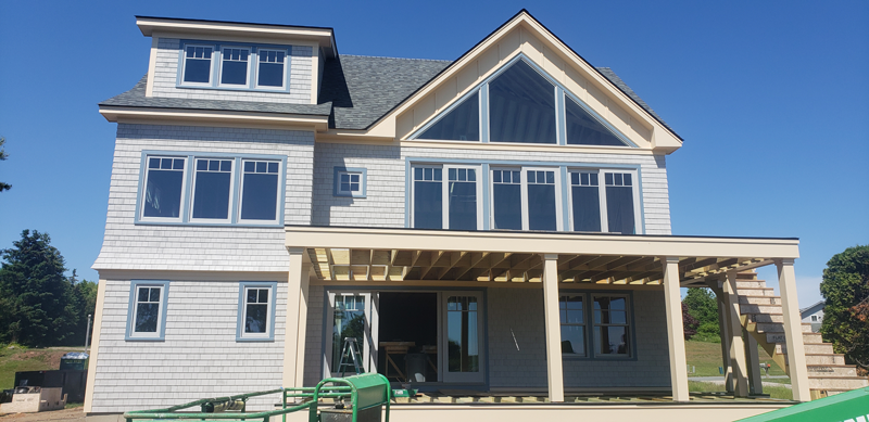 A large white house with a large porch is being built.