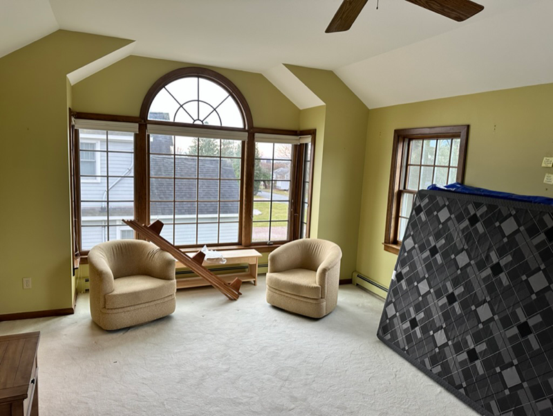 A living room with two chairs and a mattress on the floor