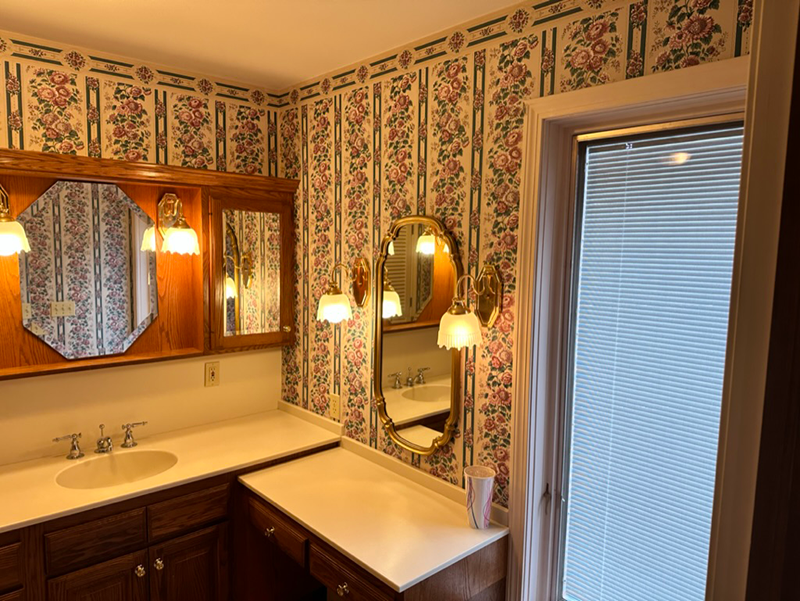 A bathroom with a sink , mirror and floral wallpaper