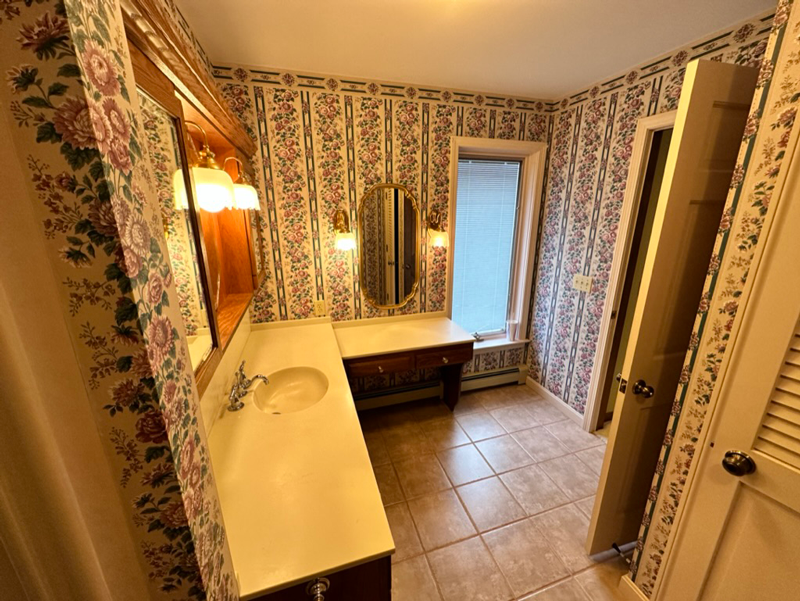 A bathroom with a sink , mirror and floral wallpaper