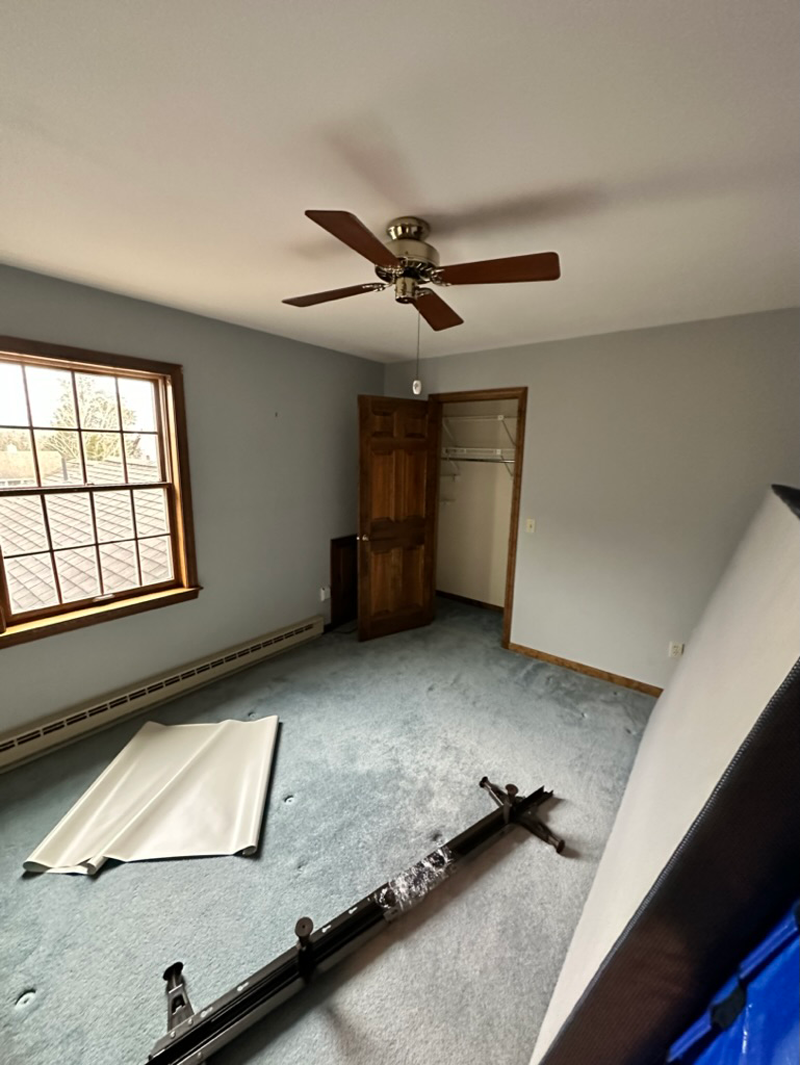 An empty bedroom with a ceiling fan and a window.