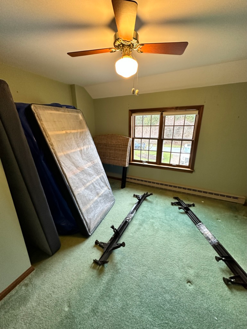 A bedroom with a ceiling fan and a mattress on the floor.