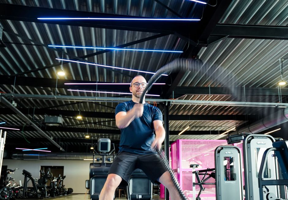 Een man houdt een touw vast in een sportschool.