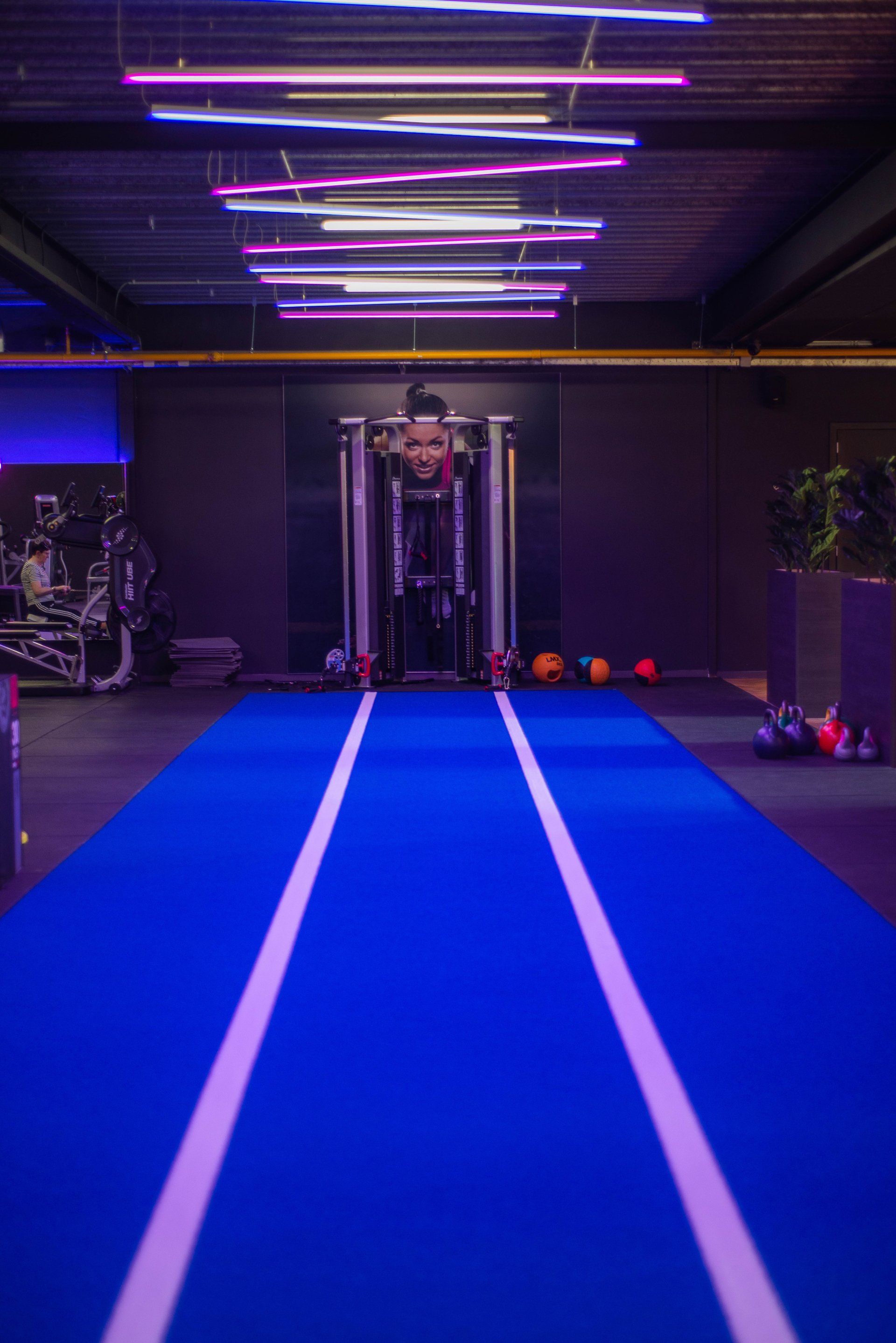 Een persoon staat op een blauwe mat in een sportschool.