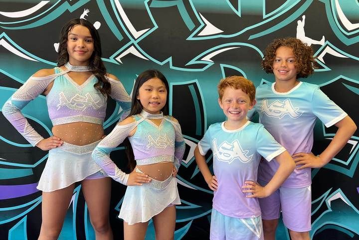 A group of cheerleaders are posing for a picture in front of a graffiti wall.