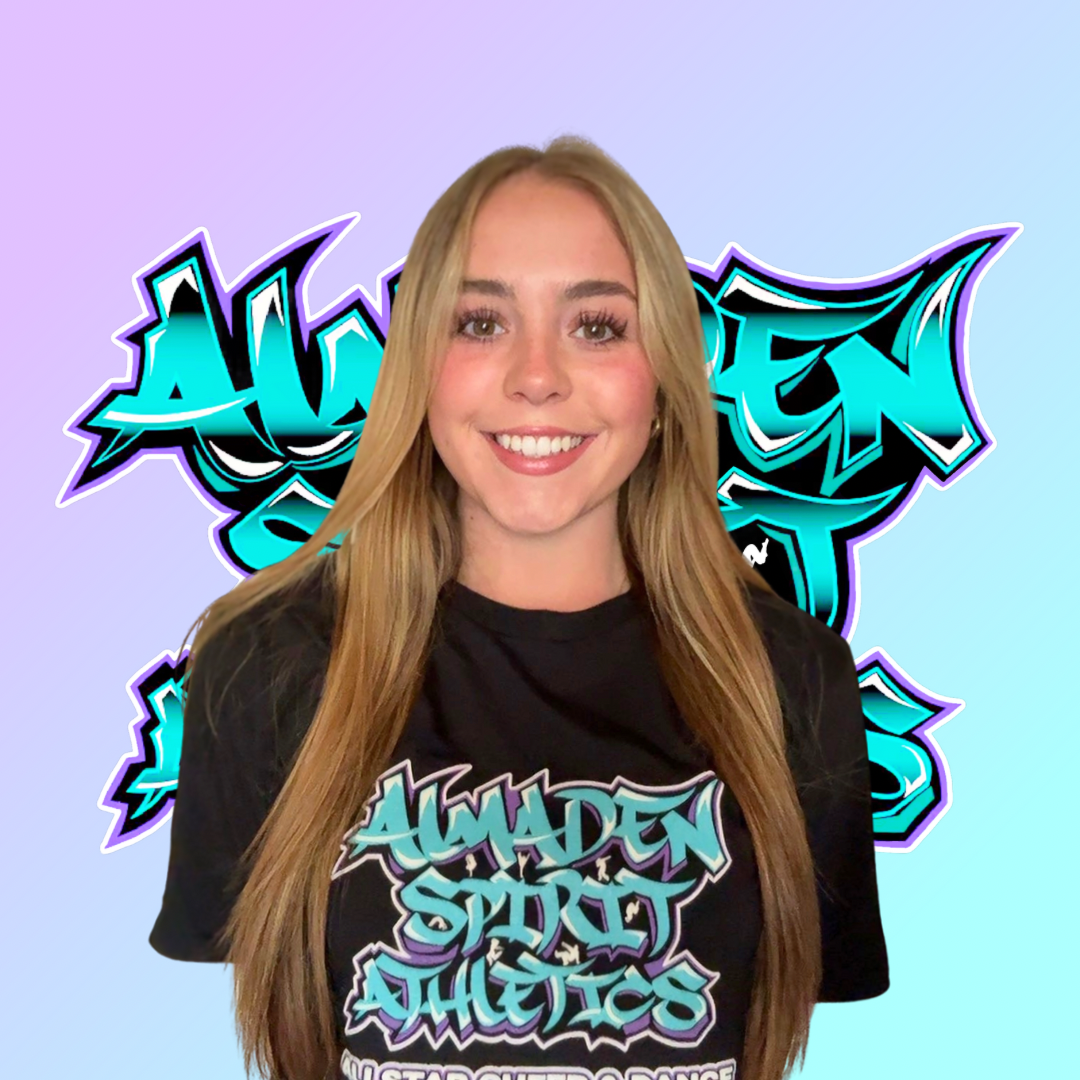 A young woman wearing a black t-shirt is smiling in front of a graffiti background.