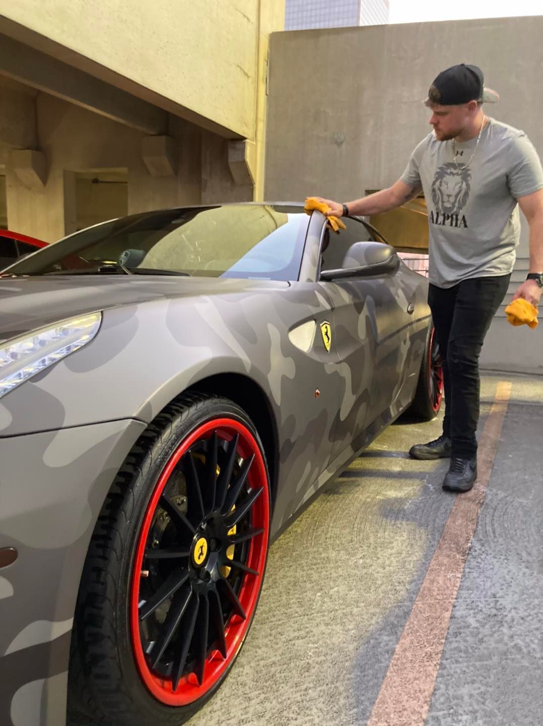 A man is polishing the side of a car in a garage.