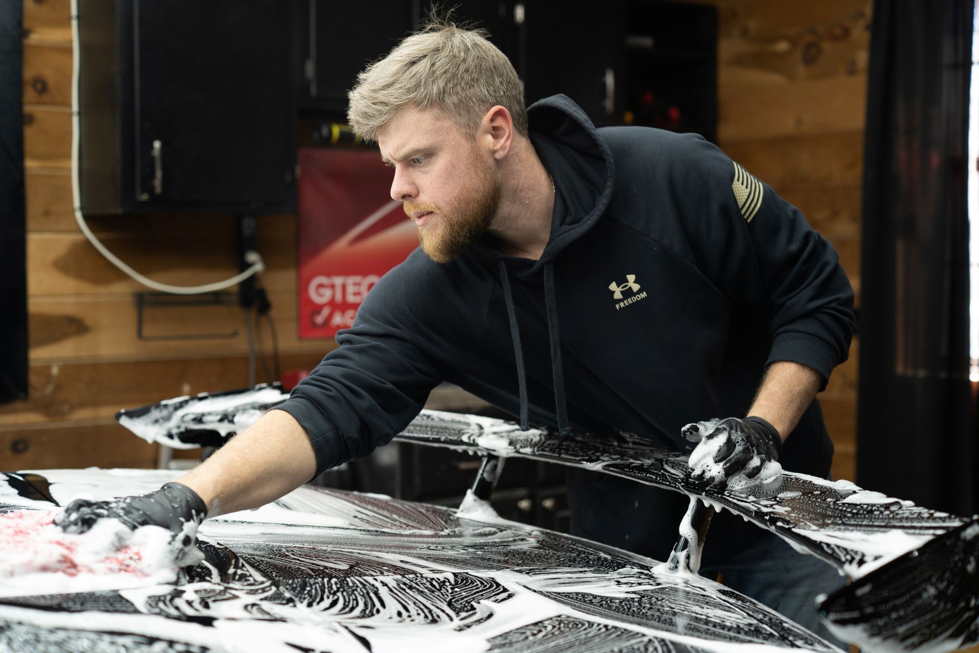 A man is washing a car in a garage.