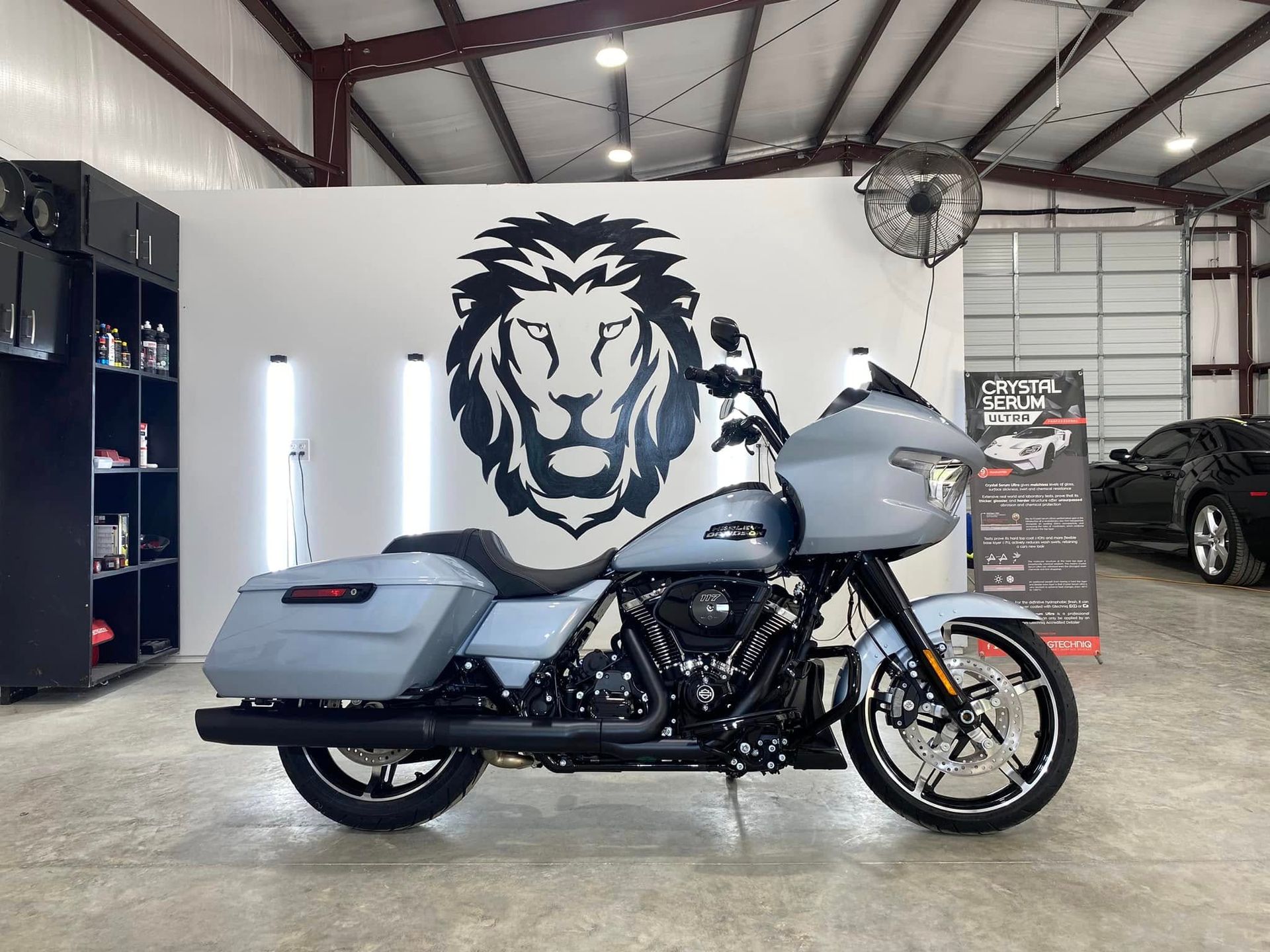 A motorcycle is parked in a garage with a lion on the wall.