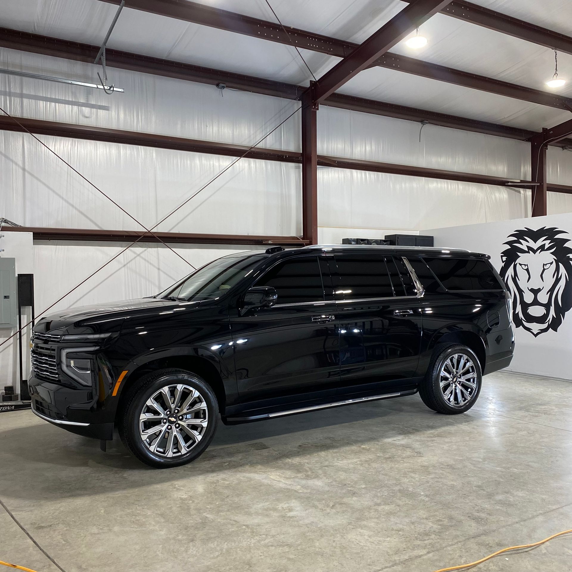 A black suv is parked in a garage with a lion on the wall.