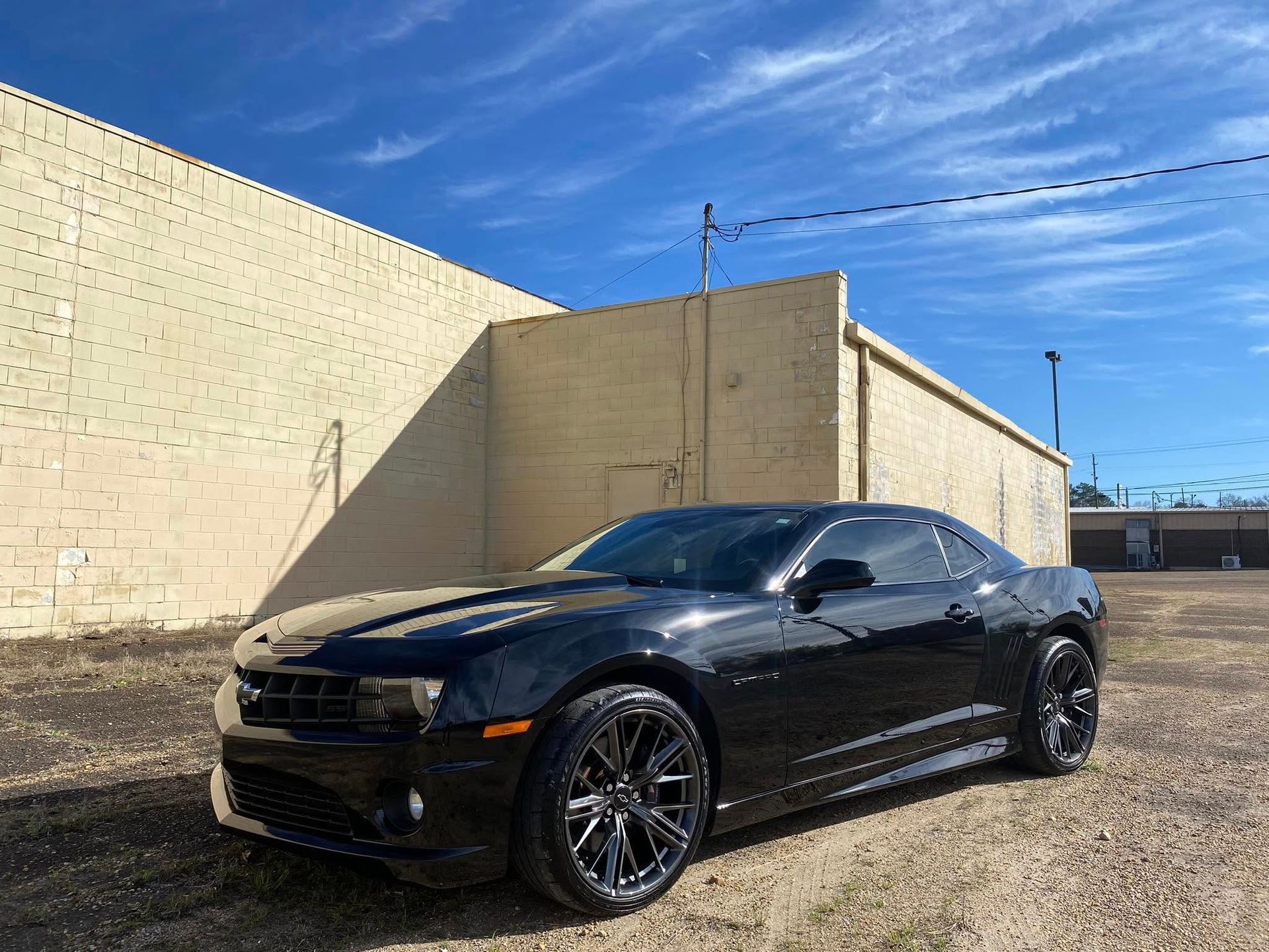 A black car is parked in front of a brick building.