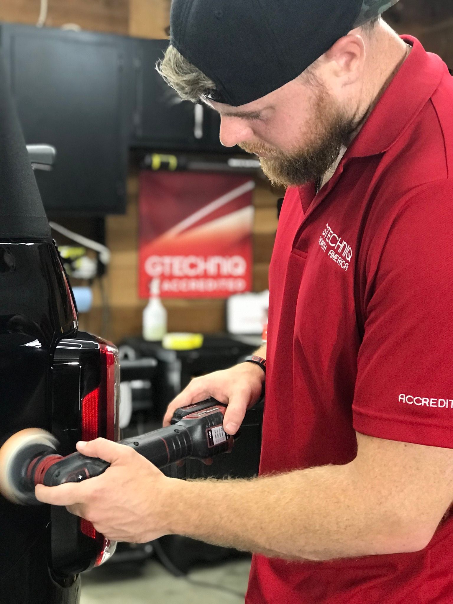 A man in a red shirt is polishing a car.