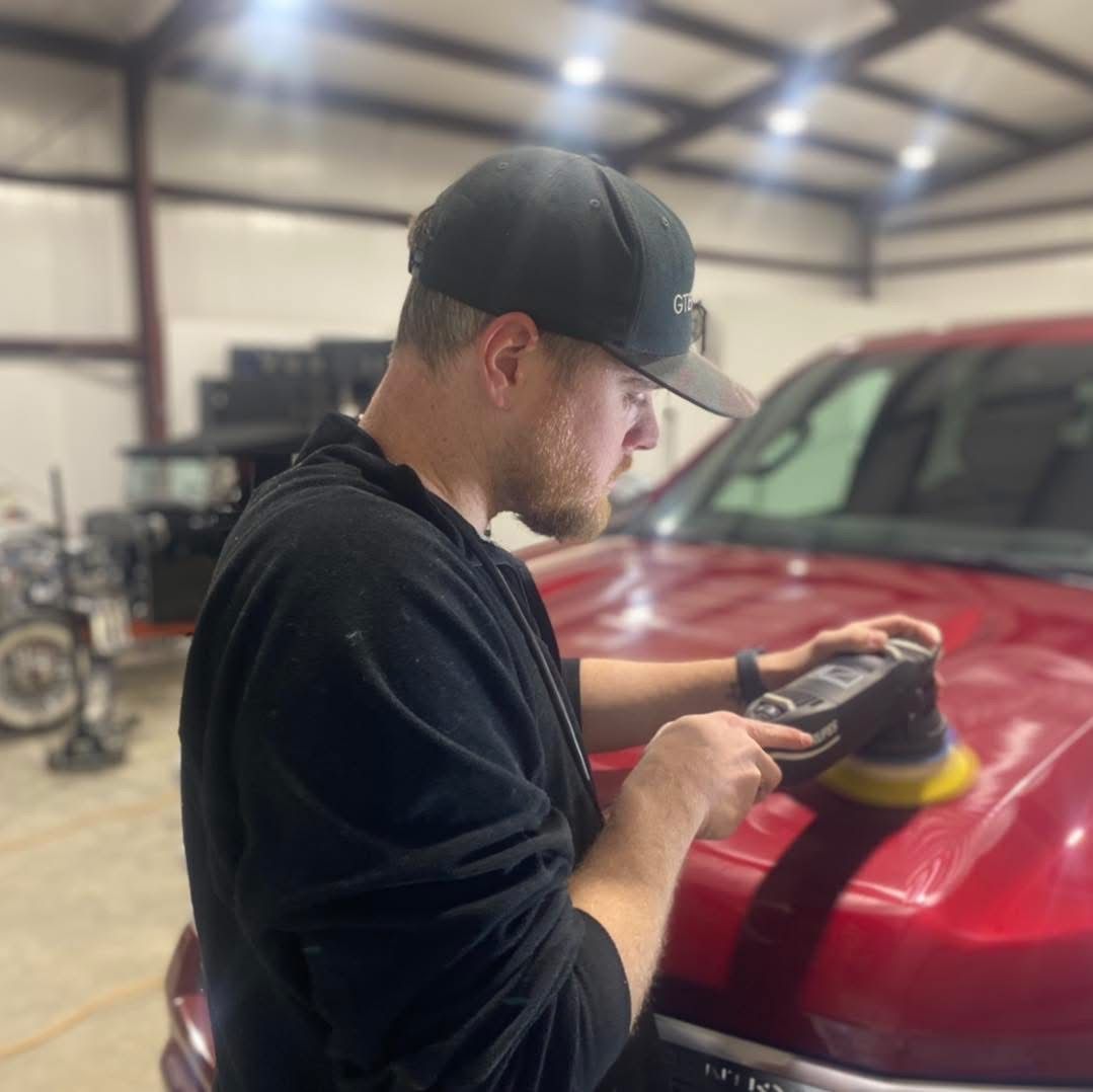 A man is polishing the hood of a red truck