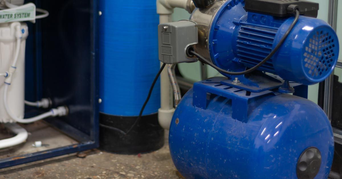 A blue water pump is sitting next to a blue tank.