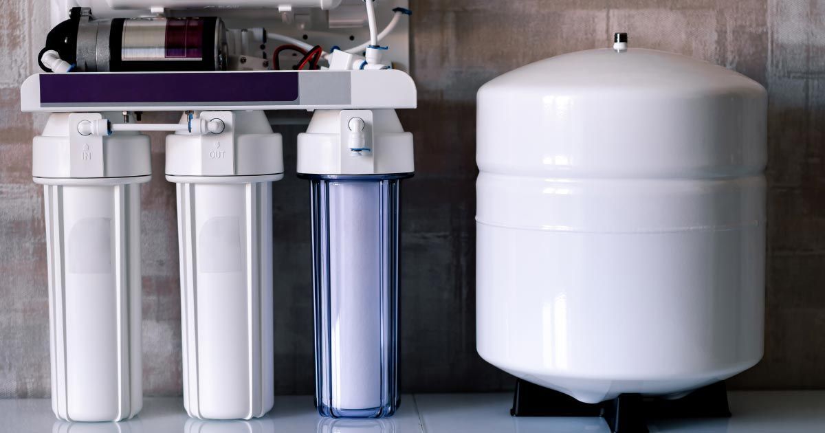 A water filter is sitting next to a tank.