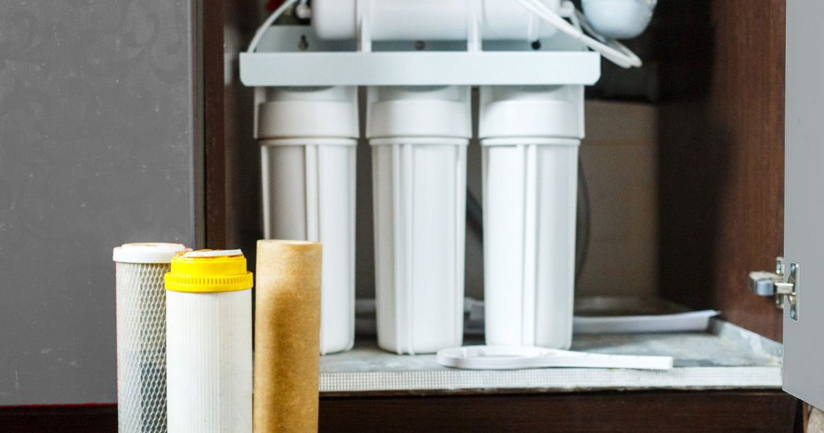 A water filter is sitting inside of a cabinet.