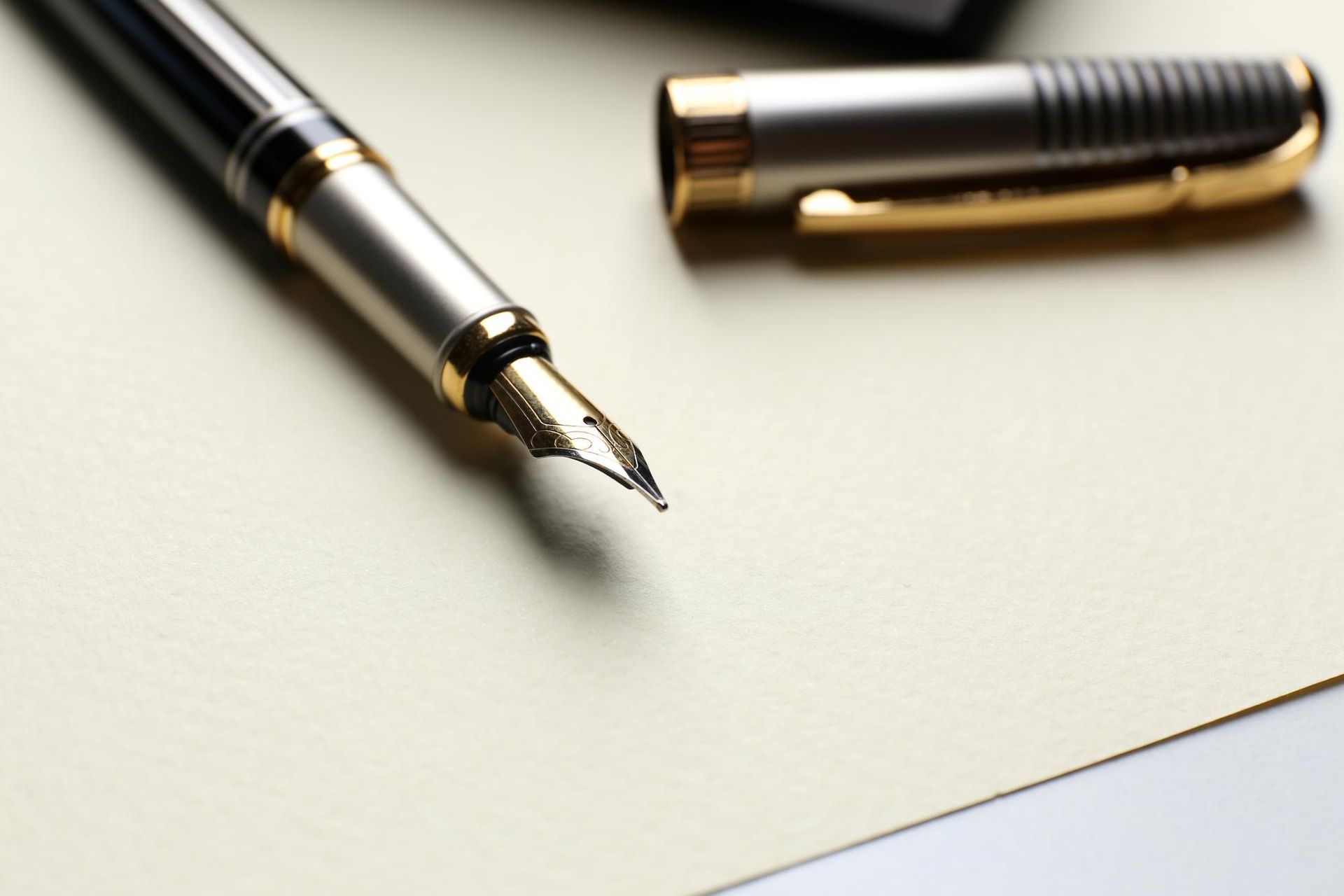 Fountain pen with gold accents rests on a blank, off-white paper.