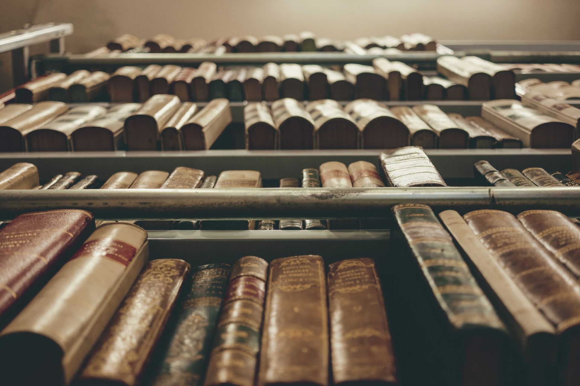 Bookshelves filled with old books, viewed from a low angle. Leather and aged paper.