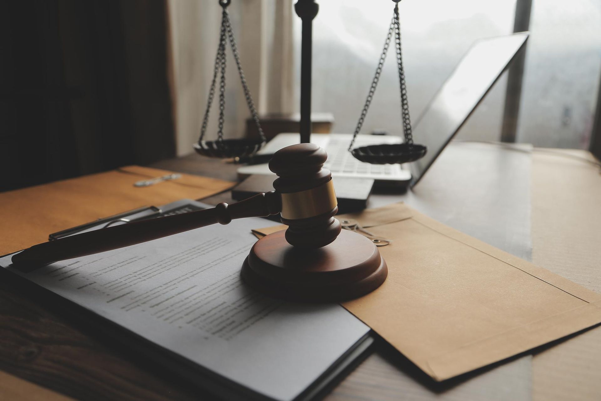 Gavel, scales of justice, and documents on a desk with a laptop, symbolizing legal work.
