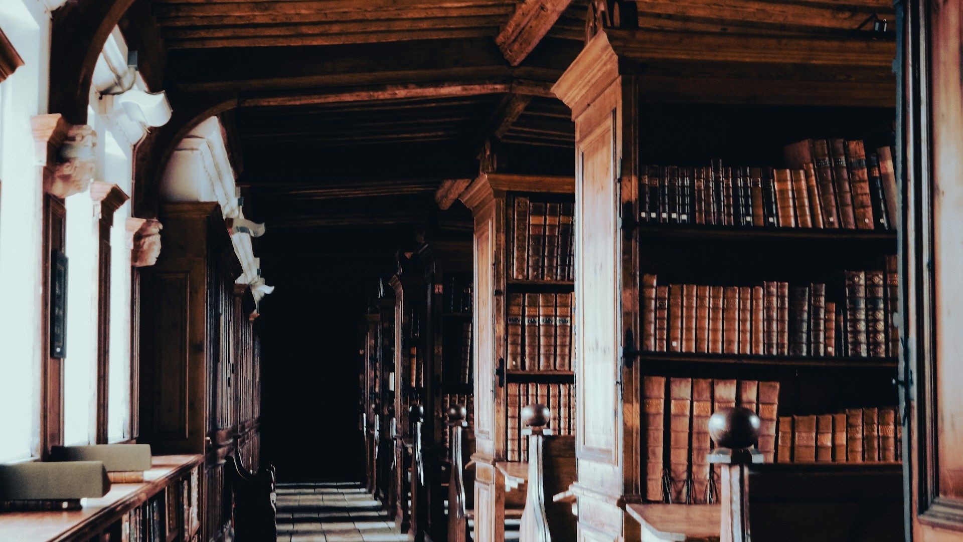 Dark library with wooden shelves filled with old books.