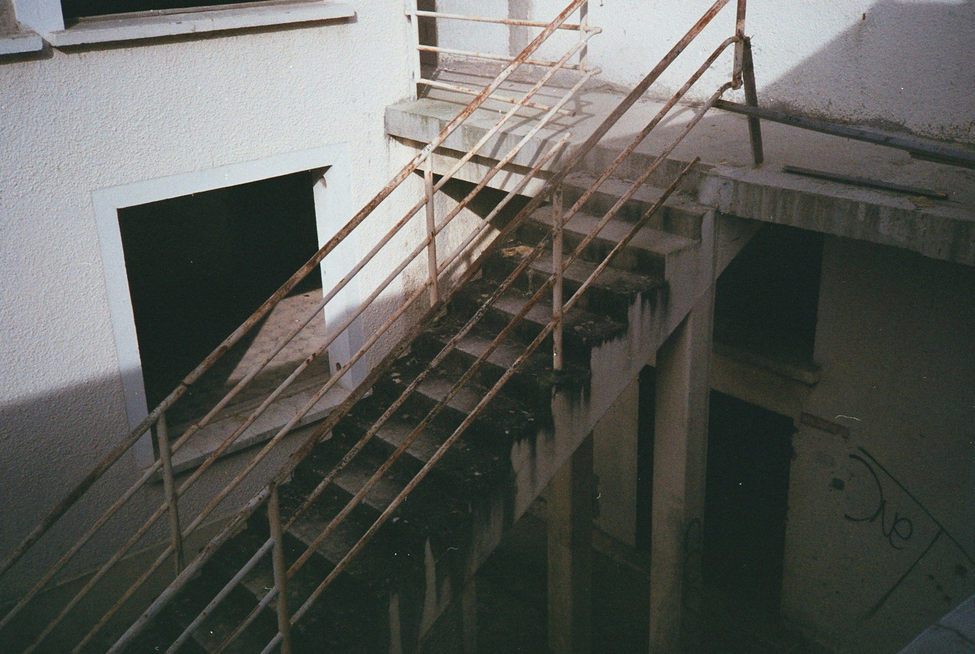 Exterior concrete staircase with rusty metal railings.