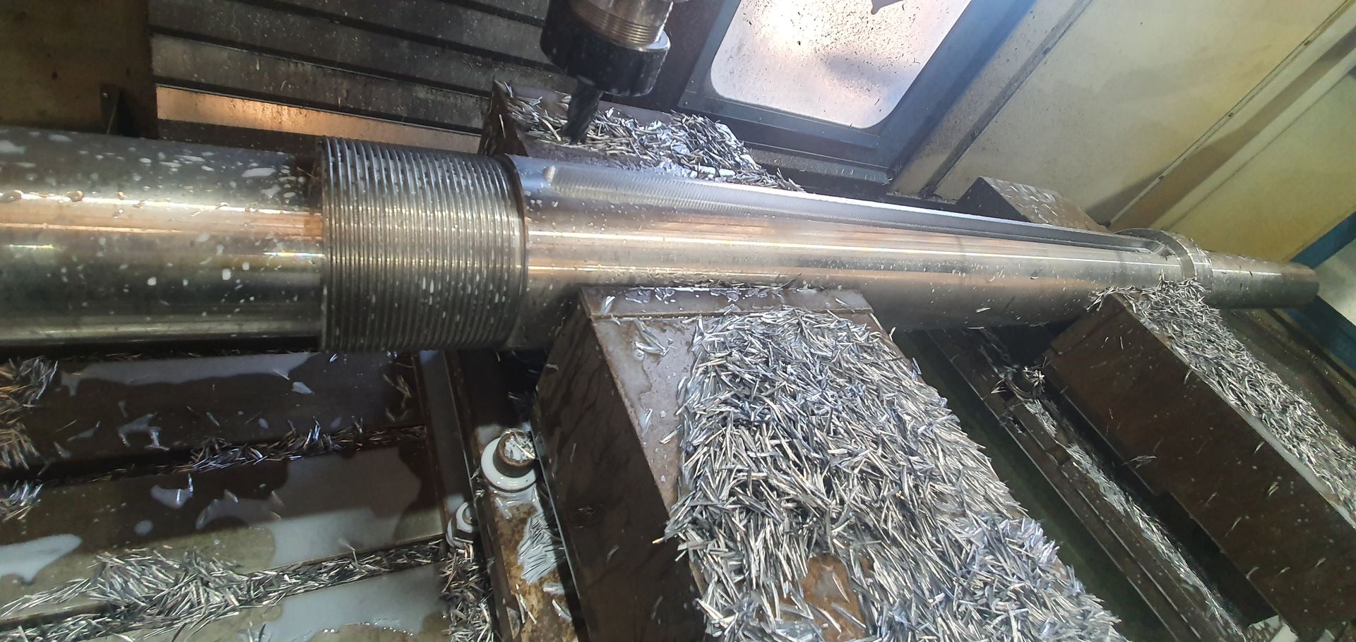 A machine is cutting a piece of metal on a lathe.