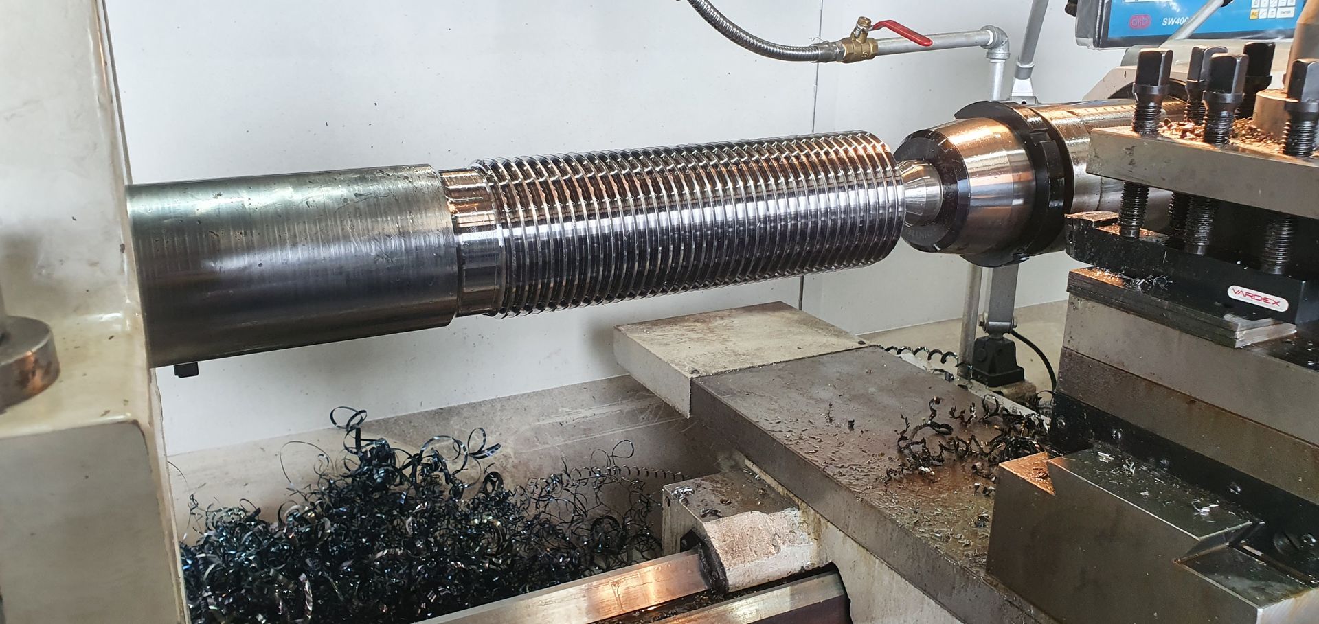 A machine is cutting a piece of metal on a lathe.