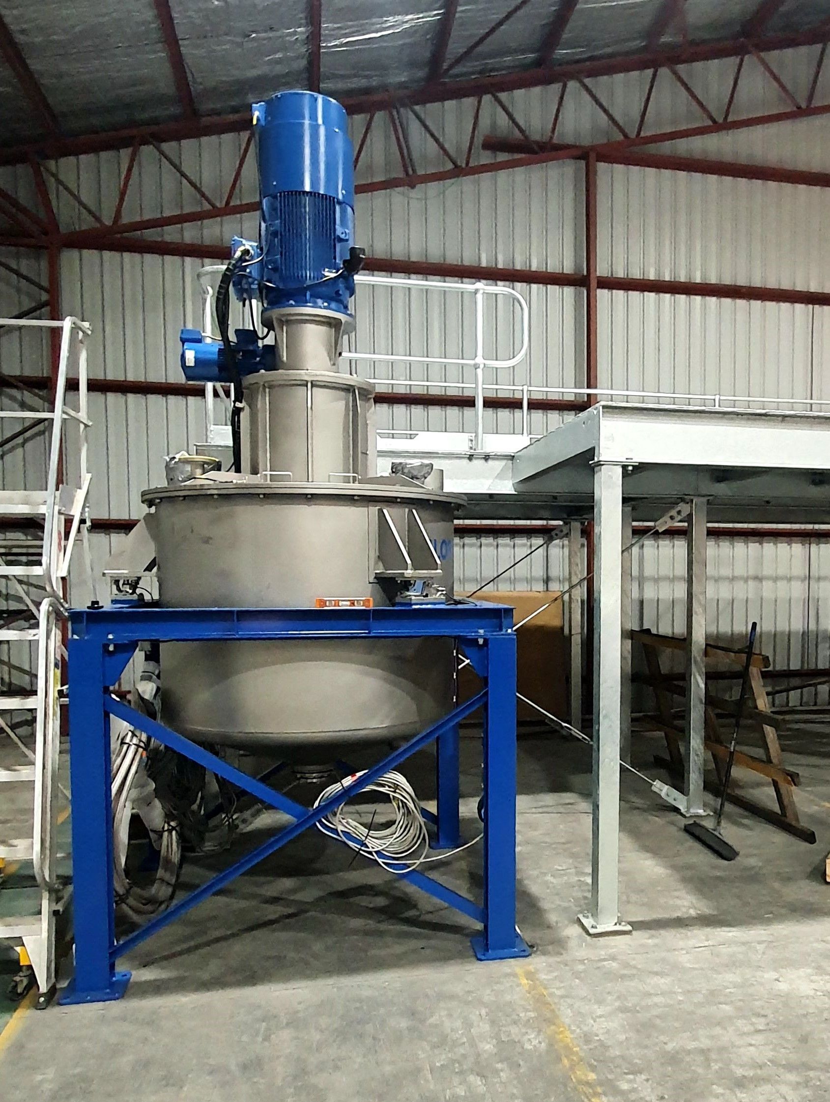 A large stainless steel mixer is sitting in a warehouse.