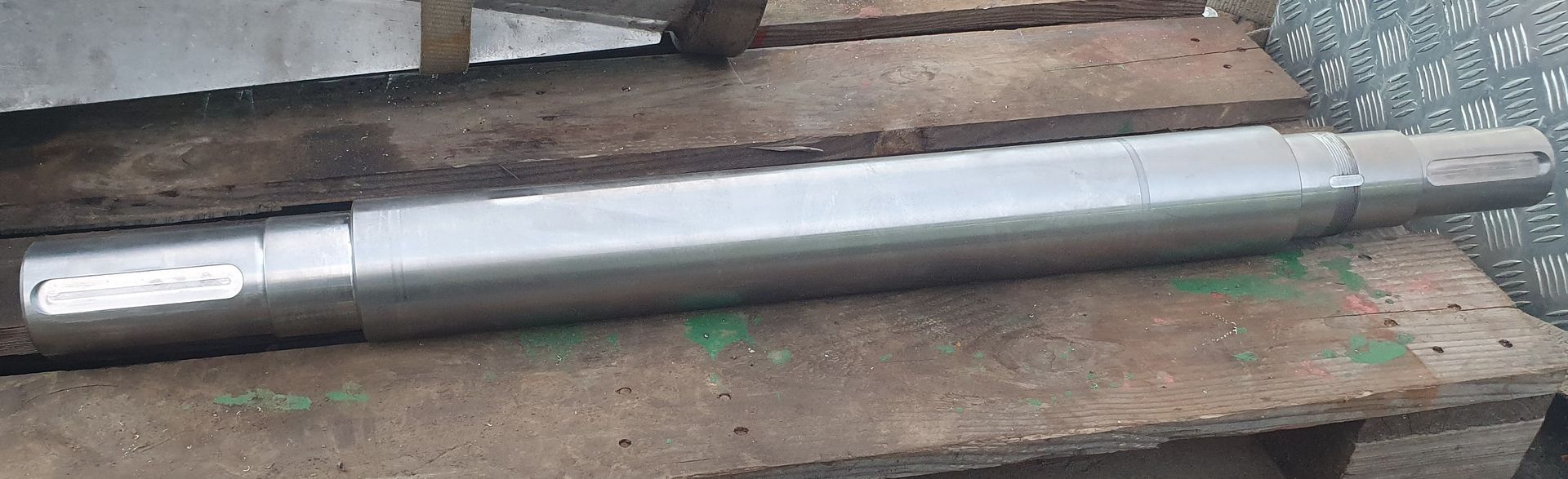 A metal pipe is sitting on top of a wooden pallet.