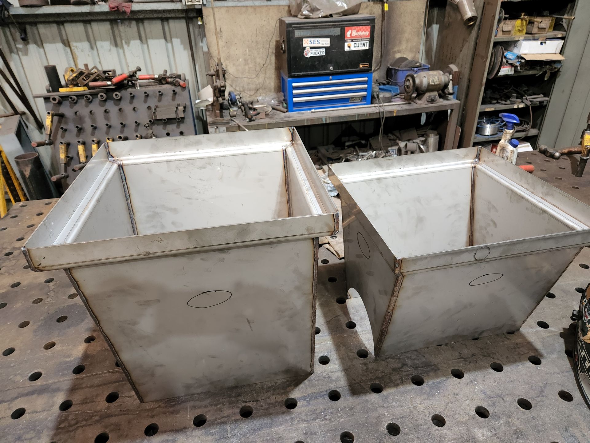 Two stainless steel bins are sitting on top of a wooden table.