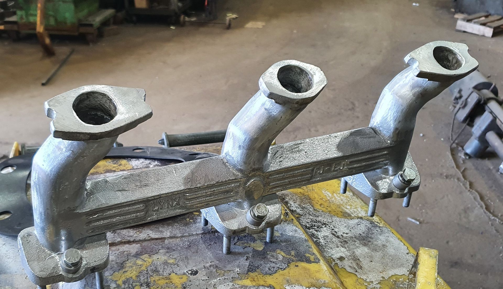 A metal pipe with three holes in it is sitting on a table.