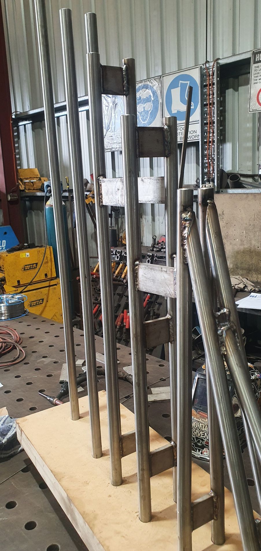 A row of metal poles sitting on top of a wooden table in a factory.