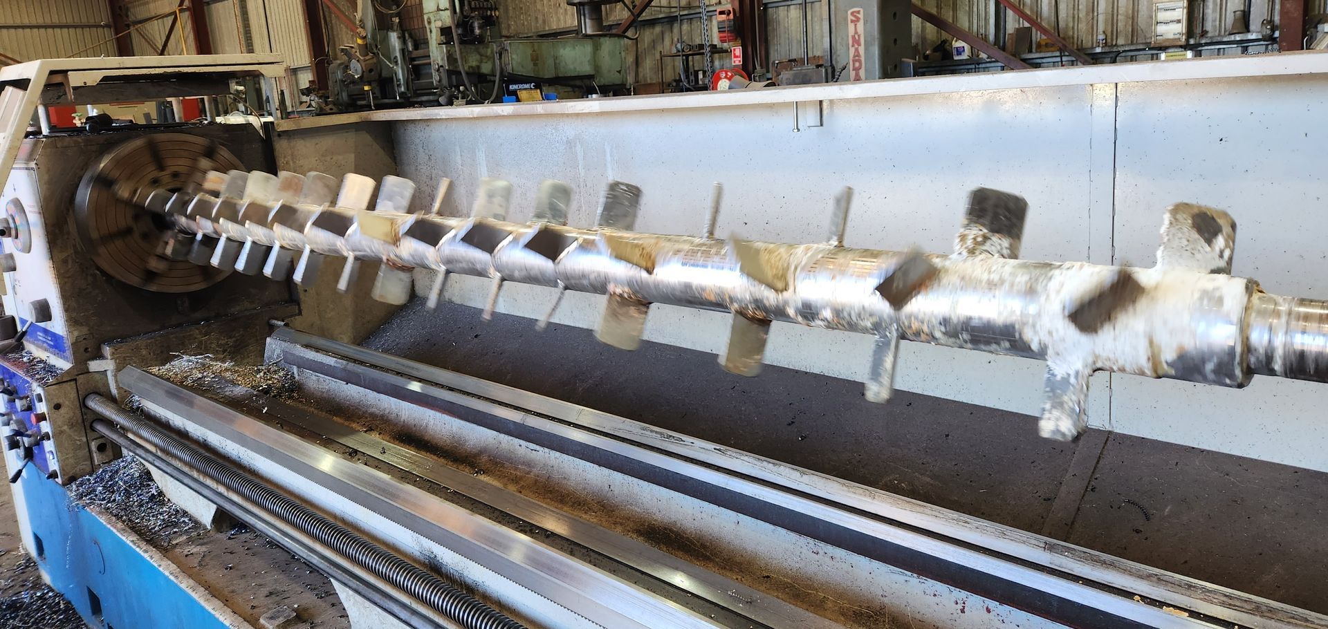 A large metal pipe is being turned on a lathe in a factory.