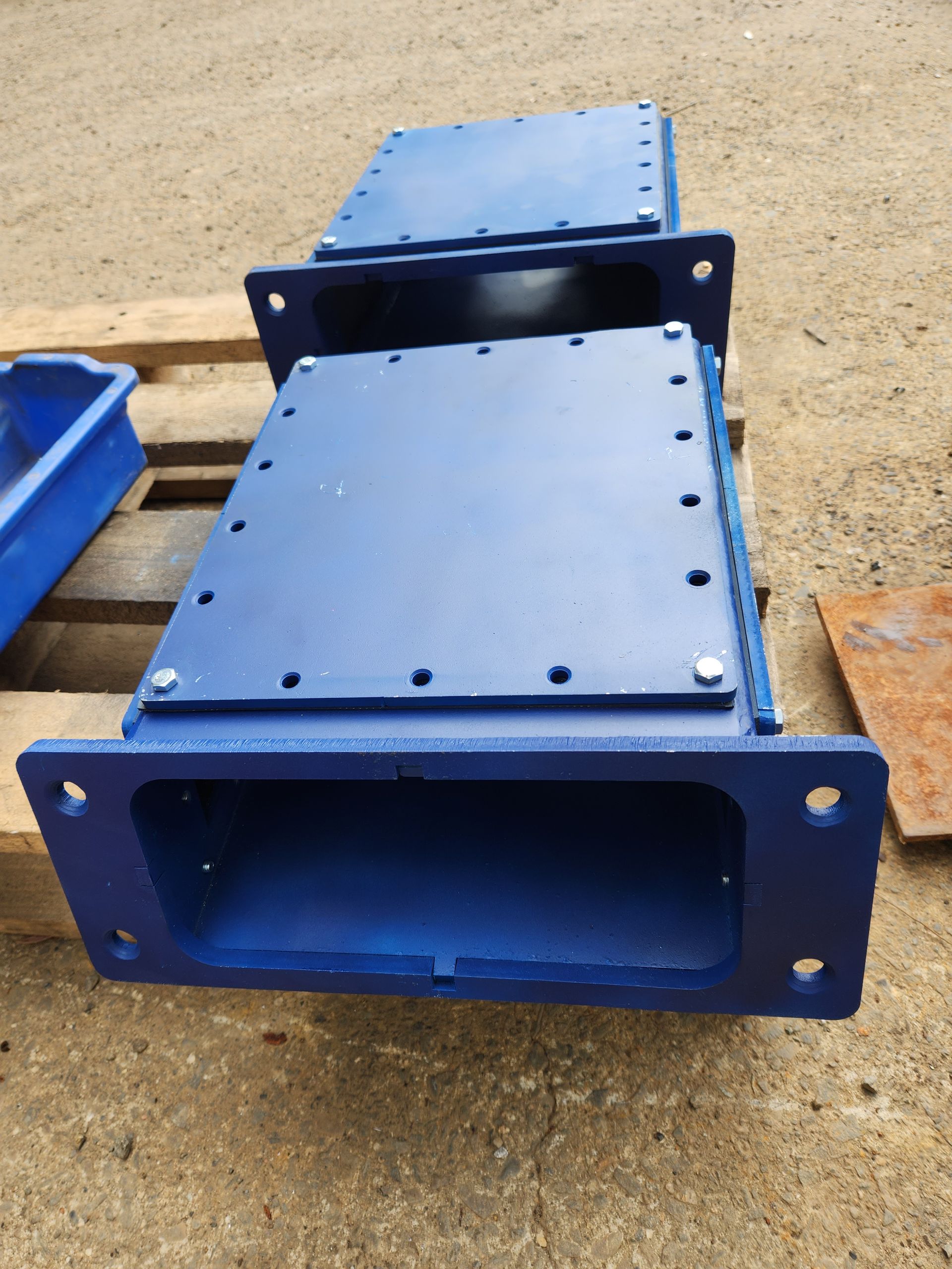 Two blue metal boxes are sitting on a wooden pallet