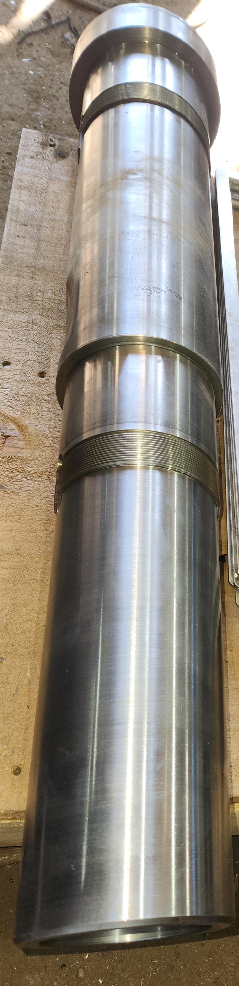 A large metal pipe is sitting on top of a brick wall.