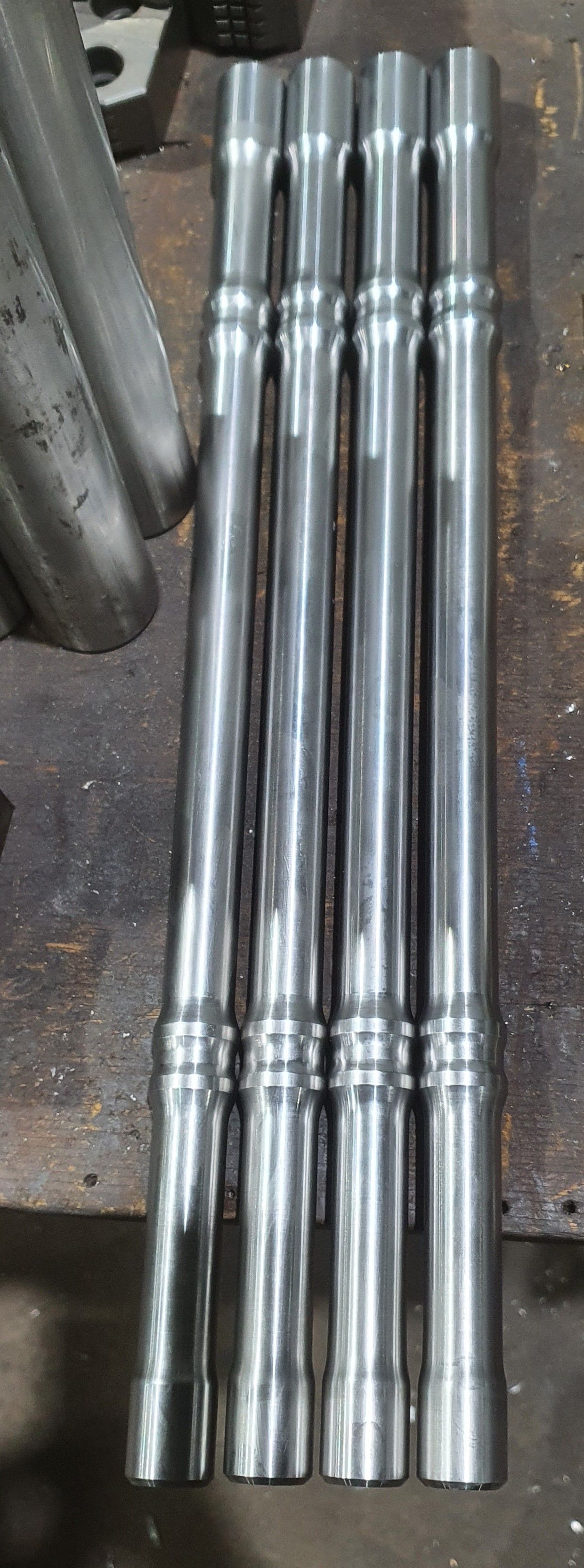 A bunch of metal pipes sitting on top of each other on a table.