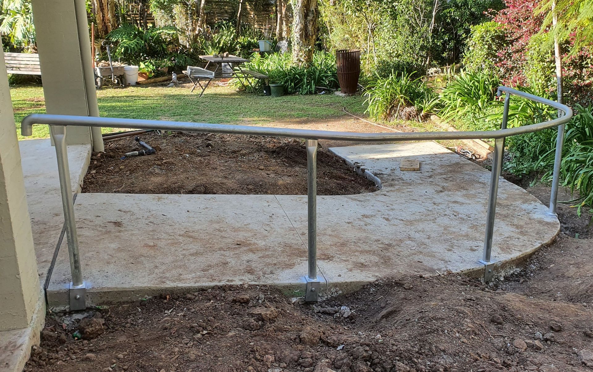 A stainless steel railing is sitting on top of a concrete walkway.