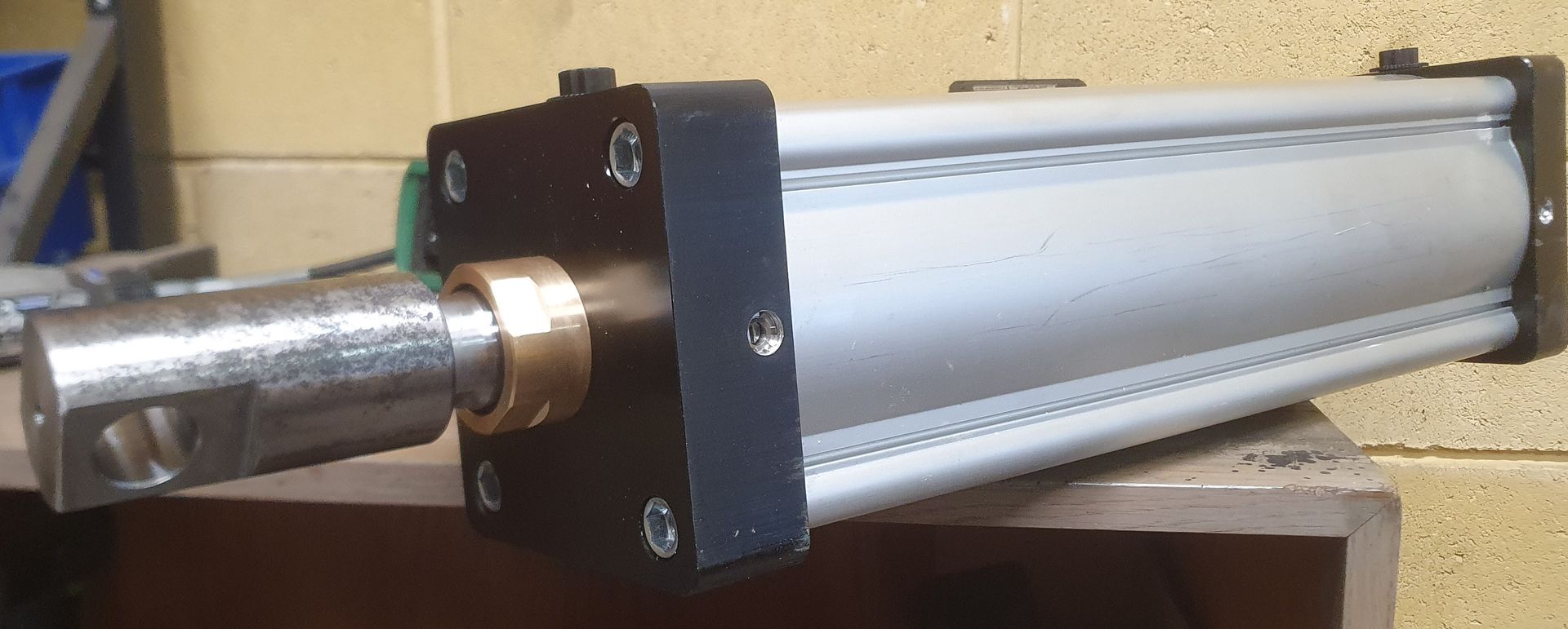 A metal cylinder is sitting on a table in front of a brick wall.