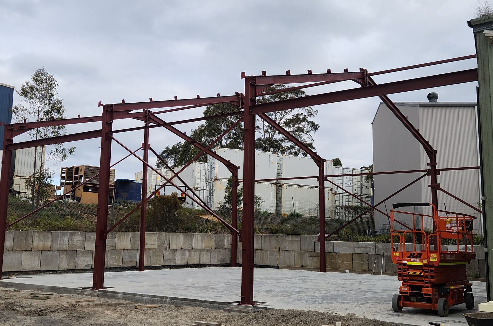 A large metal structure is being built in a parking lot.