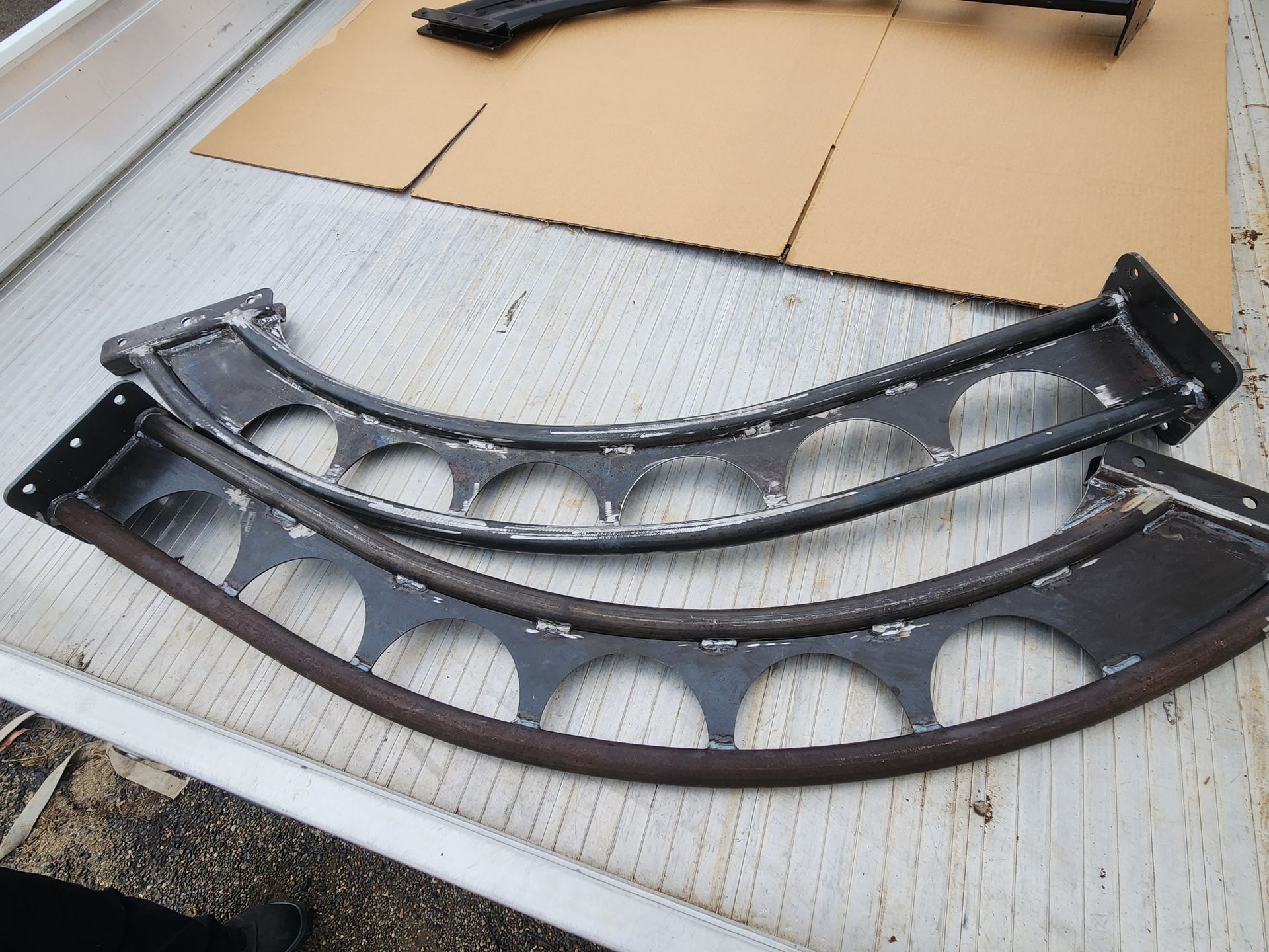 Two curved metal pieces are laying on a cardboard box