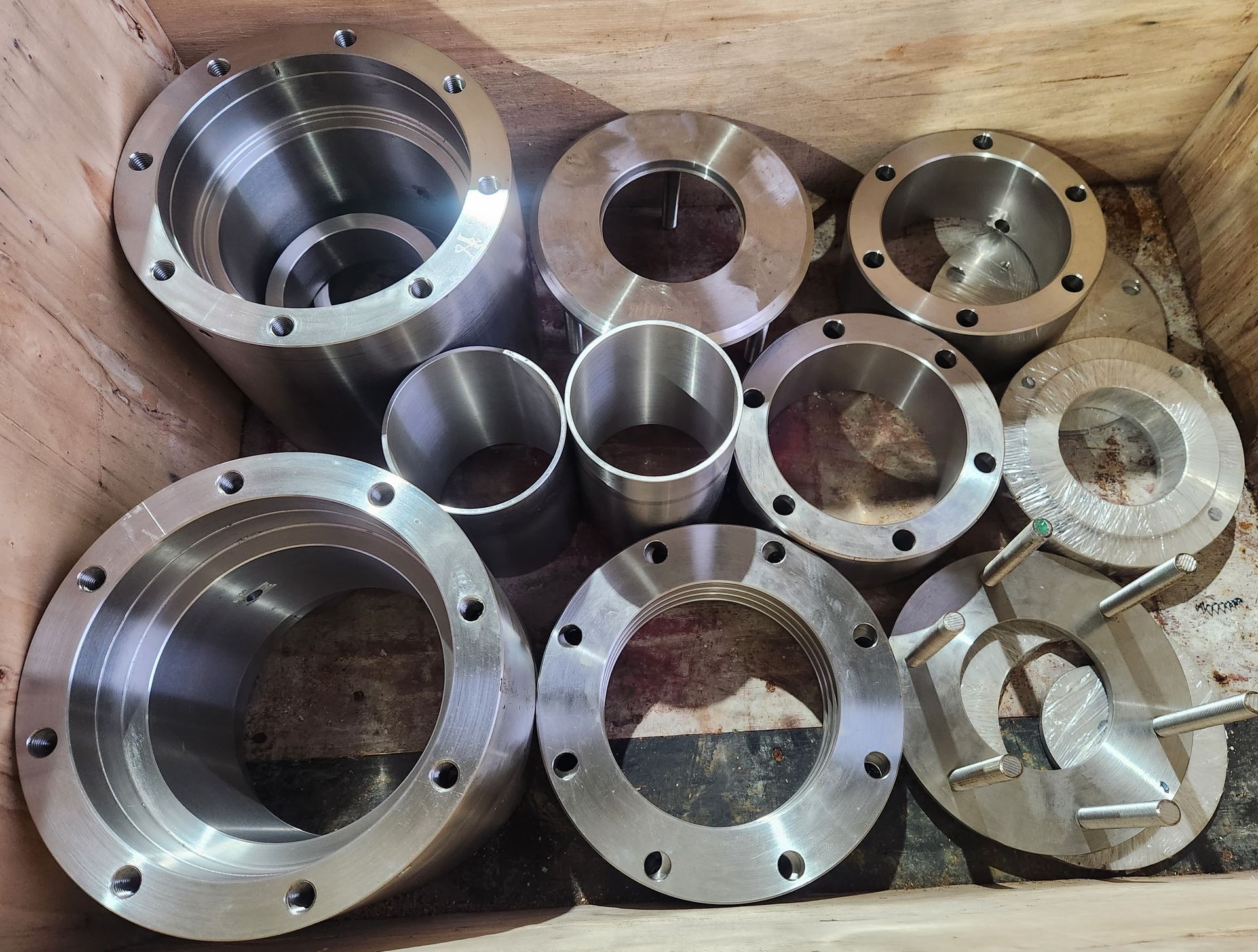 A wooden box filled with a variety of metal parts.