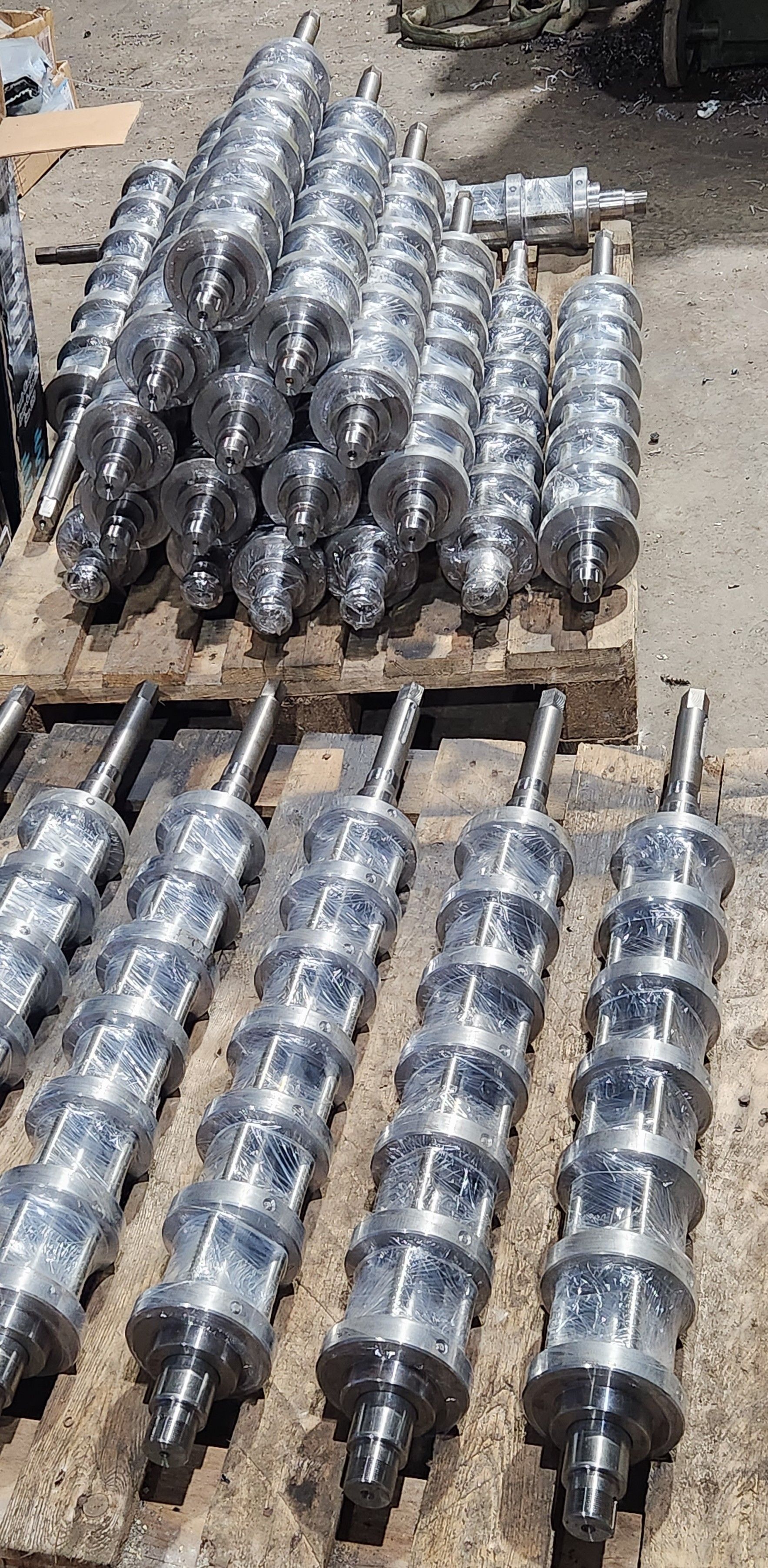 A bunch of metal cylinders are stacked on top of each other on a wooden pallet.