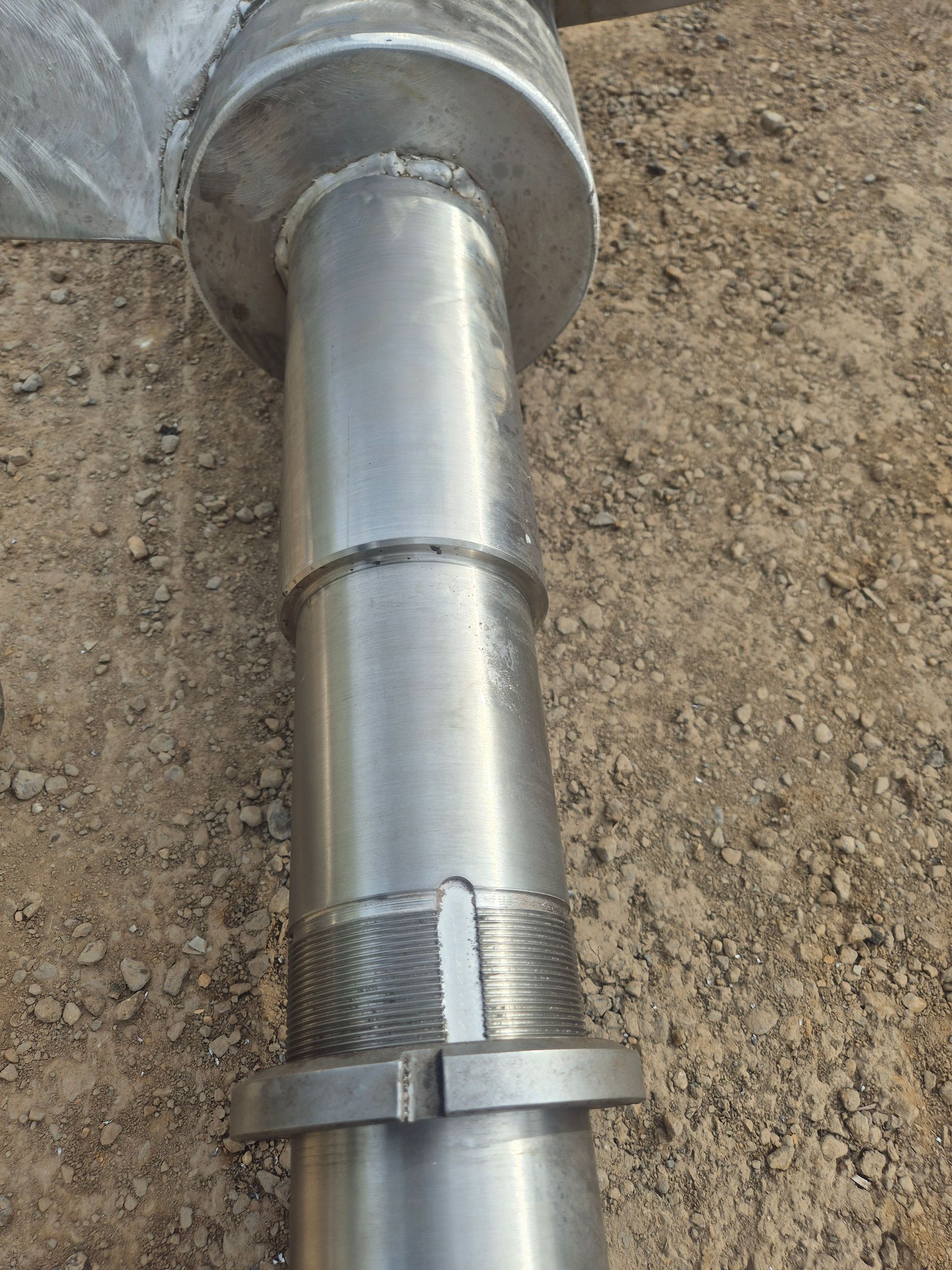 A metal pipe is sitting on top of a pile of dirt.