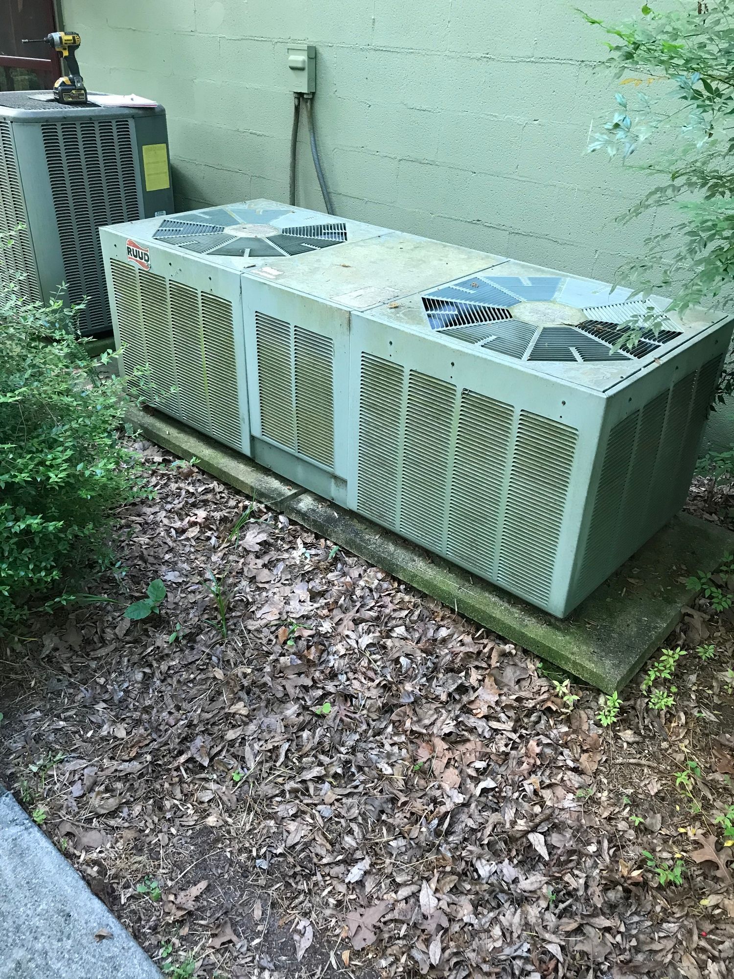 A large air conditioner is sitting on the ground next to a wall.