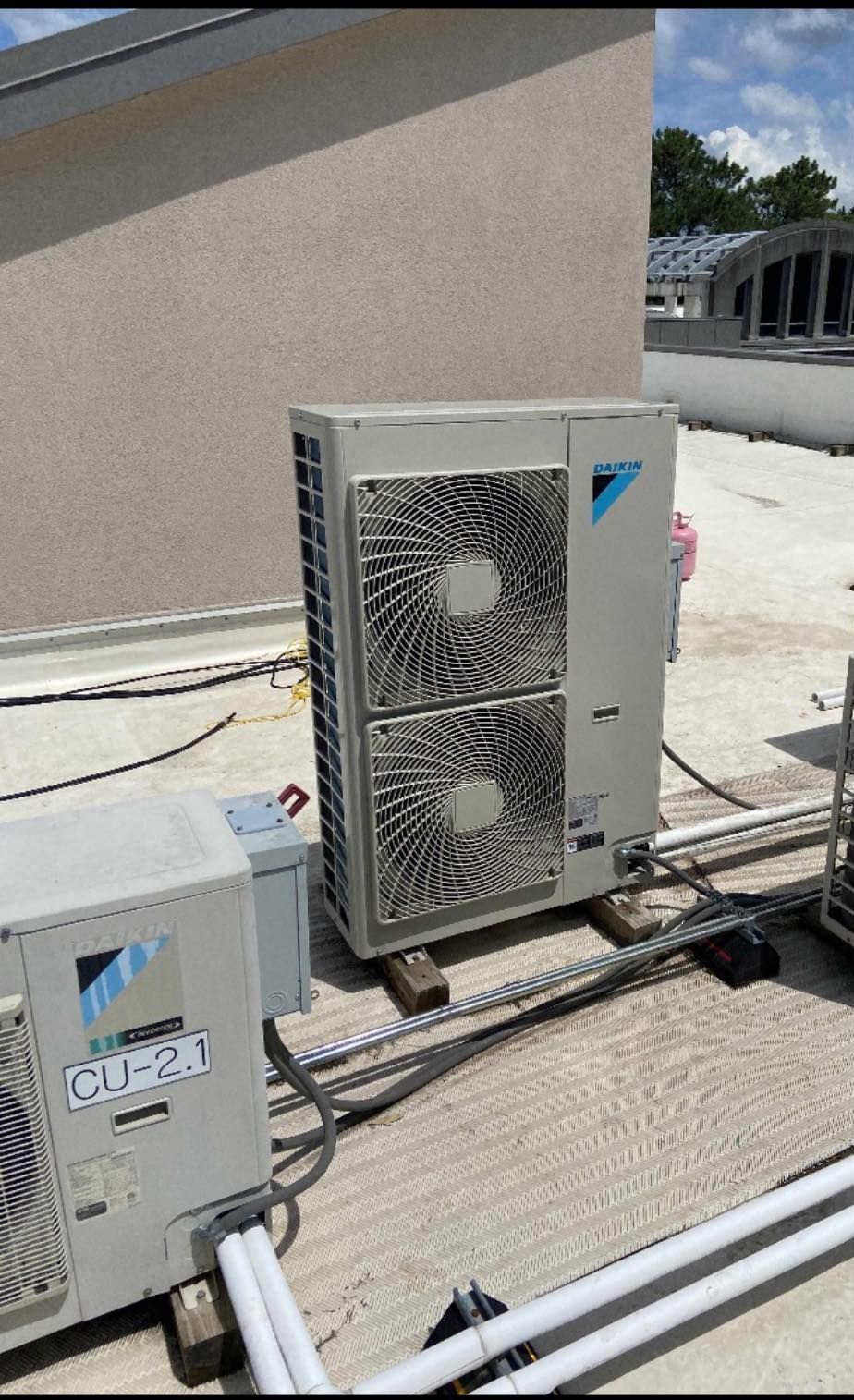 Two air conditioners are sitting on the roof of a building.