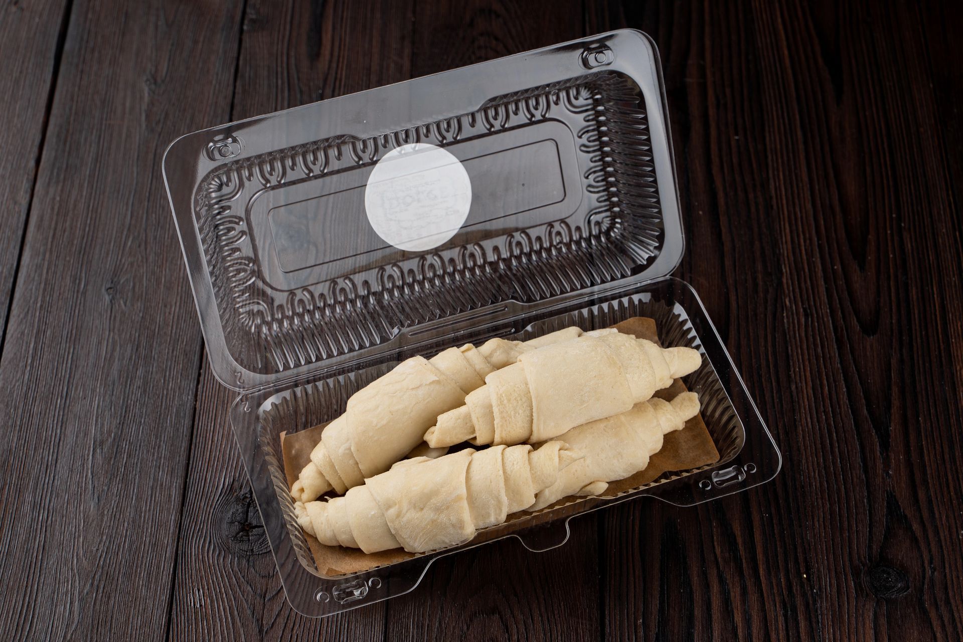 Carne di manzo cruda e congelata, già affettata, su un tagliere di legno con sacchetti di carne congelata sullo sfondo.