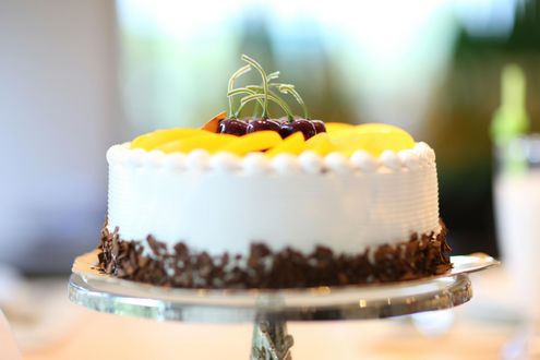 A cake with fruit on top of it is on a cake stand.